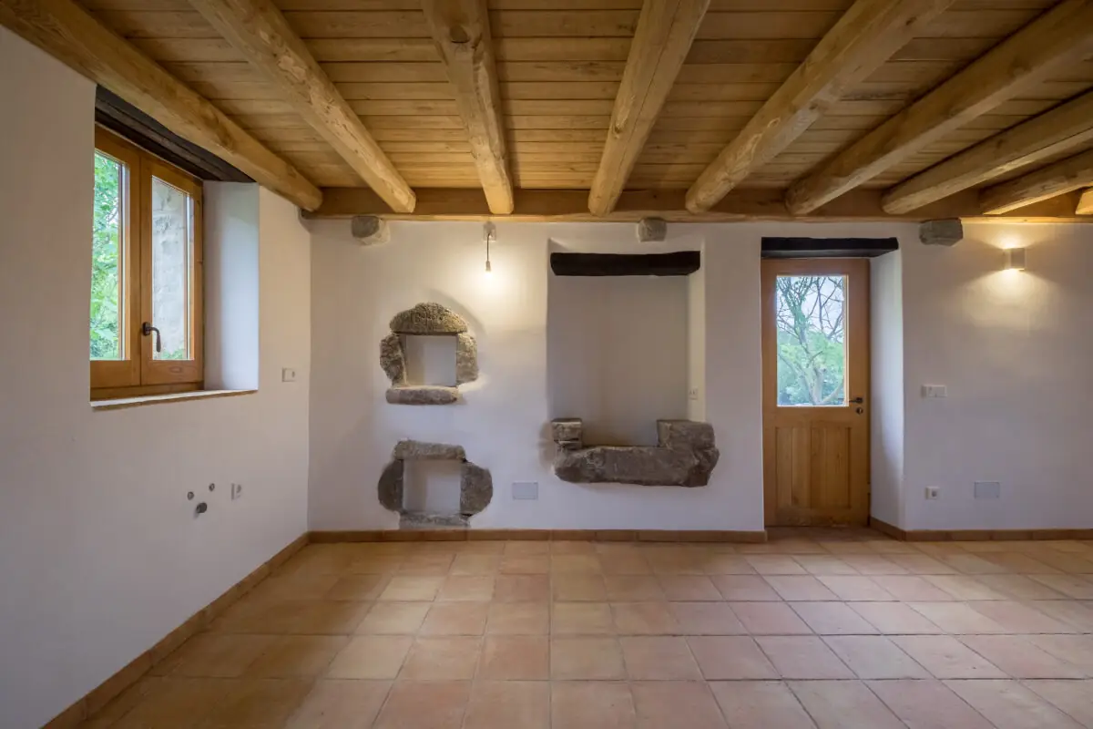 Sala rehabilitada d’una masia, amb bigues de fusta vistes i parets de calç